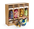 A child is putting his wellies on in front of a set of cubbies