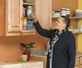 Teacher taking a bottle of paint out of a wall-mounted cabinet