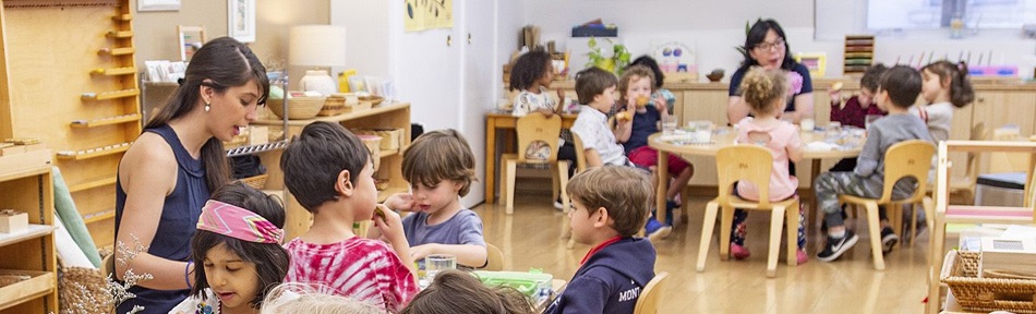 An early years classroom with children sitting on chairs around tables