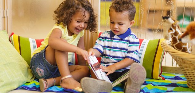 A boy and girl looking at a book in an EYFS classroom