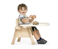 A child sits on a chair with tray and plays with a wooden car