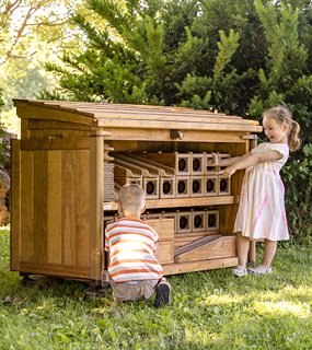 a boy putting a block in a shed