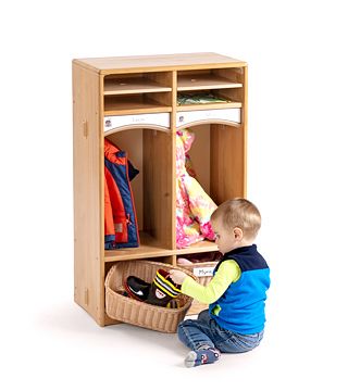 A boy stores his wellies in the basket of a Toddler Cubby